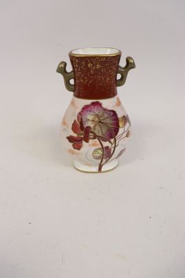 un petit vase orné d'une fleur, posé sur une surface blanche