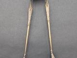 an antique silverware spoon and tonget on a gray surface