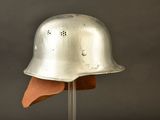 silver helmet on a stand against a gray background