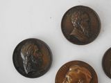 three bronze medallions of a man and a woman on a white surface