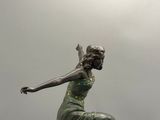 une statue représentant une femme en robe verte, au sommet d'un immeuble