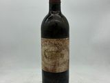 une vieille bouteille de vin posée sur une table blanche