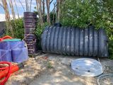 a large black tank sitting next to a couple of blue barrels