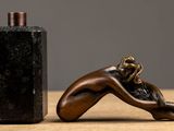 a bottle of perfume next to a statue of a woman