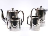 two silver teapots sitting next to each other on a white surface