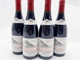 quatre bouteilles de vin rouge sont alignées sur une surface blanche