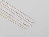 three gold chain necklaces on a white background