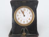 a small clock that is on a stand on a white surface
