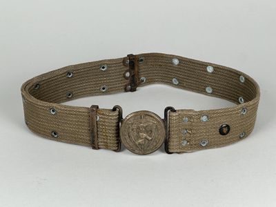 une ceinture munie d'une boucle métallique, posée sur une surface blanche