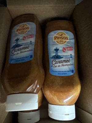 deux bouteilles de condiment sont posées dans une boîte en carton sur une table