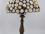 une lampe de table ornée de coquillages, dont le cordon est branché sur le socle