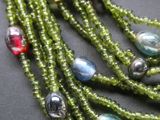 un gros plan sur un collier vert composé de perles multicolores