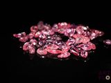 some pink diamonds on a black surface with a black background