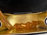 a black and gold purse with a gold chain around it