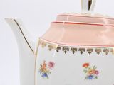 a white tea pot with a pink lid and flowers on it