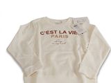 Le pull est blanc et comporte une inscription en rouge.