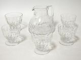 four glasses and a pitcher sitting on a table