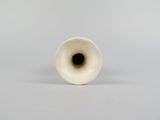a white vase that has a black hole in it