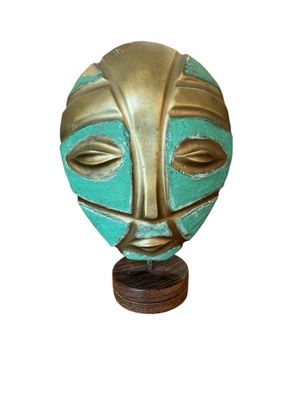 an image of a gold and turquoise mask on a wooden stand