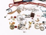 a lot of jewelry on a white table next to a cell phone