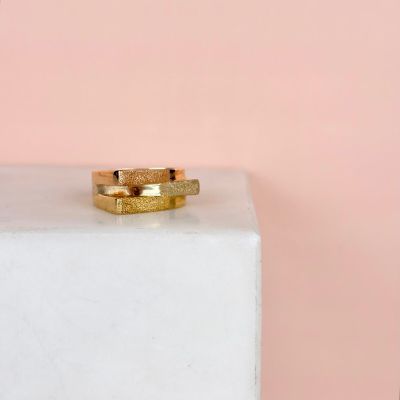 un gros plan d'une bague en or posée sur un bloc blanc