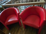 two red chairs sitting next to each other on a wooden floor