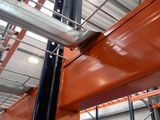 a large metal pole in a warehouse with orange paint on it