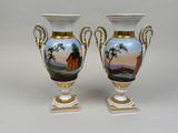pair of vases with painted landscape on them sitting on top of a table