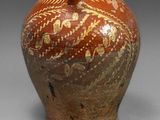un vase marron orné de motifs dorés sur un fond gris