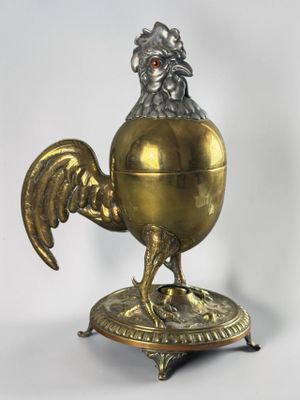 a gold colored chicken on a stand with a red eye