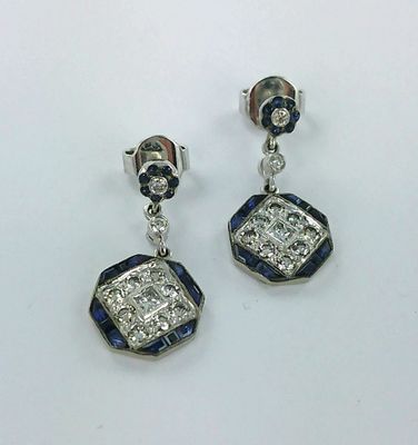 une paire de boucles d'oreilles en diamant bleu et blanc posées sur un fond blanc