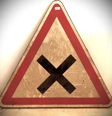 un panneau triangulaire rouge et blanc sur lequel figure un X noir