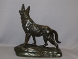 bronze statue of a dog on a rock on a white background