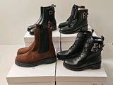 three pairs of black and brown boots sitting on top of boxes