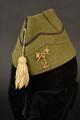 un chapeau vert orné d'un pompon, posé sur la tête d'un mannequin