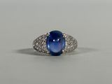 an oval blue sapphire and diamond ring on a white surface