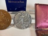 two gold and silver medals sitting on a table next to a purple box