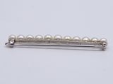 a close up of a white pearl hair pin on a white surface