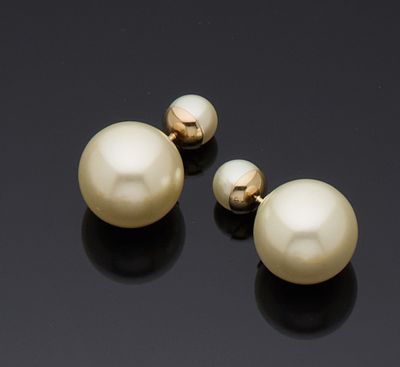 deux paires de boucles d'oreilles en perles et en or sur un fond noir