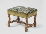 an antique foot stool with a floral upholstered seat