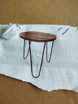 une petite table aux pieds en épingle à cheveux posée sur une feuille de papier