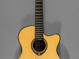 une petite guitare acoustique posée sur un support, devant un fond gris