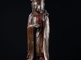une statue en bronze représentant un Bouddha assis sur un fond noir