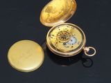a gold pocket watch sitting on a black surface