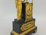 a gold and black clock with a statue on top of it