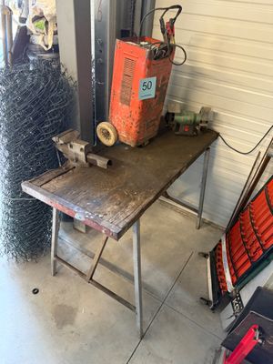 une petite table sur laquelle est posée une soudeuse, dans un garage