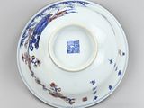 underside view of a blue and white saucer with a design of birds and flowers