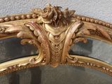 a mirror that has a gold frame with a flower on it