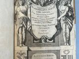 un livre ouvert sur lequel figure le dessin d'un blason et un blason