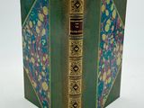 un vieux livre à la couverture verte, rehaussée de dorures sur fond blanc